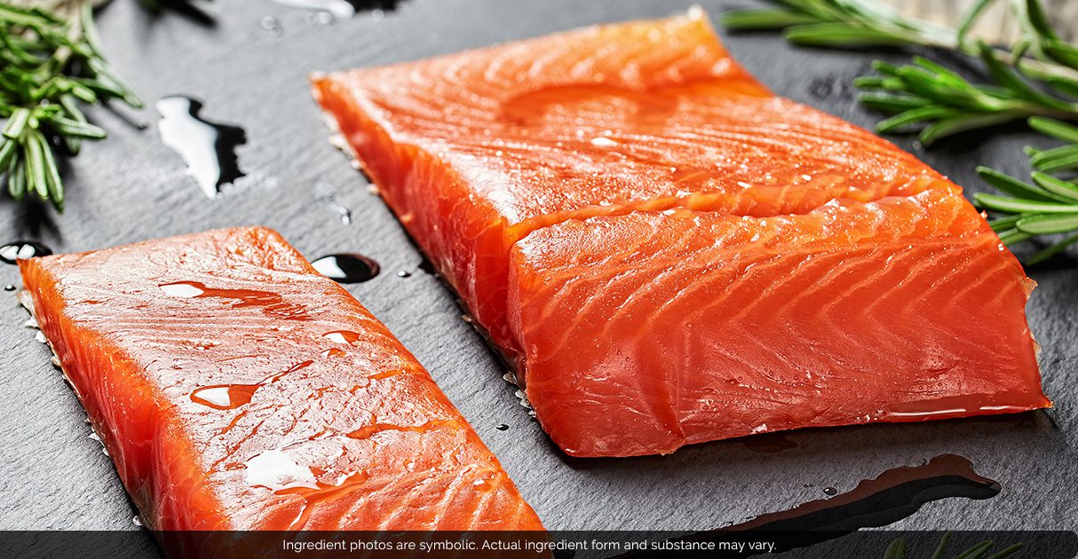 Two slices of raw fish lying on a cutting board.